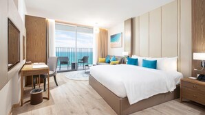 A modern hotel room with a large bed, a desk, a chair, and a view of the sea through a balcony. - Homie Panorama Nha Trang (Nha Trang)