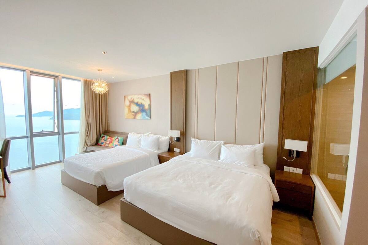 A hotel room with two beds, a large window with a view, and a modern design.