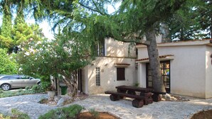 A stone-paved courtyard with a picnic table, a car parked outside, and a building with a tiled roof. - Apartment 1720/17788 (Istria - Premantura), 350m from the beach (Premantura)