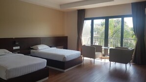 Habitación de hotel con dos camas, una mesita, una silla y un balcón con cortinas.