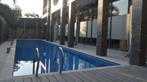 Un edificio moderno con piscina, ventanas amplias y terraza de madera.