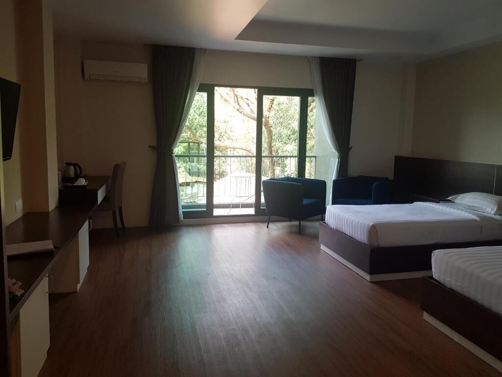 Habitación de hotel con una cama grande, un escritorio con silla y vistas a un área exterior por una puerta de vidrio.