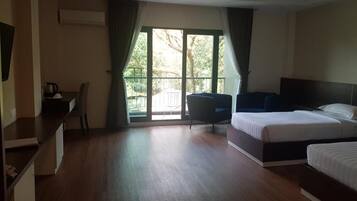Habitación de hotel con una cama grande, un escritorio con silla y vistas a un área exterior por una puerta de vidrio.