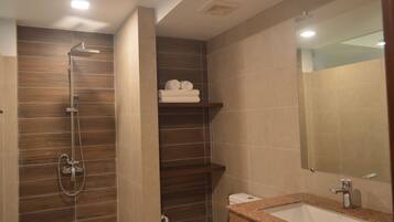 Een badkamer met een douche, wastafel, toilet en spiegel.