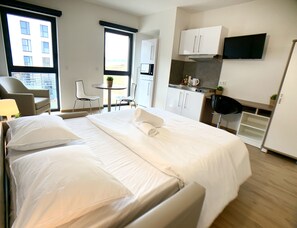 A hotel room with a large bed, a desk, a chair, a small table, and a TV. - Cozy Studio, Open Space, Business & Leisure (Esch-sur-Alzette)