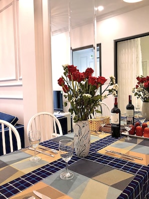 Una mesa de comedor decorada con un jarrón de rosas rojas, copas de vino y una botella de vino.