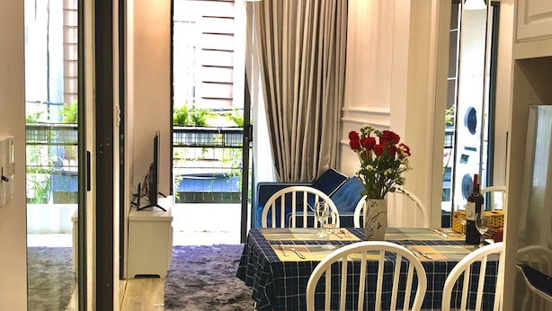 Ein Essbereich mit einem Tisch für zwei Personen, weißen Stühlen und einer Vase mit roten Blumen.