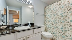 Une salle de bain avec un lavabo blanc, un miroir et des toilettes.