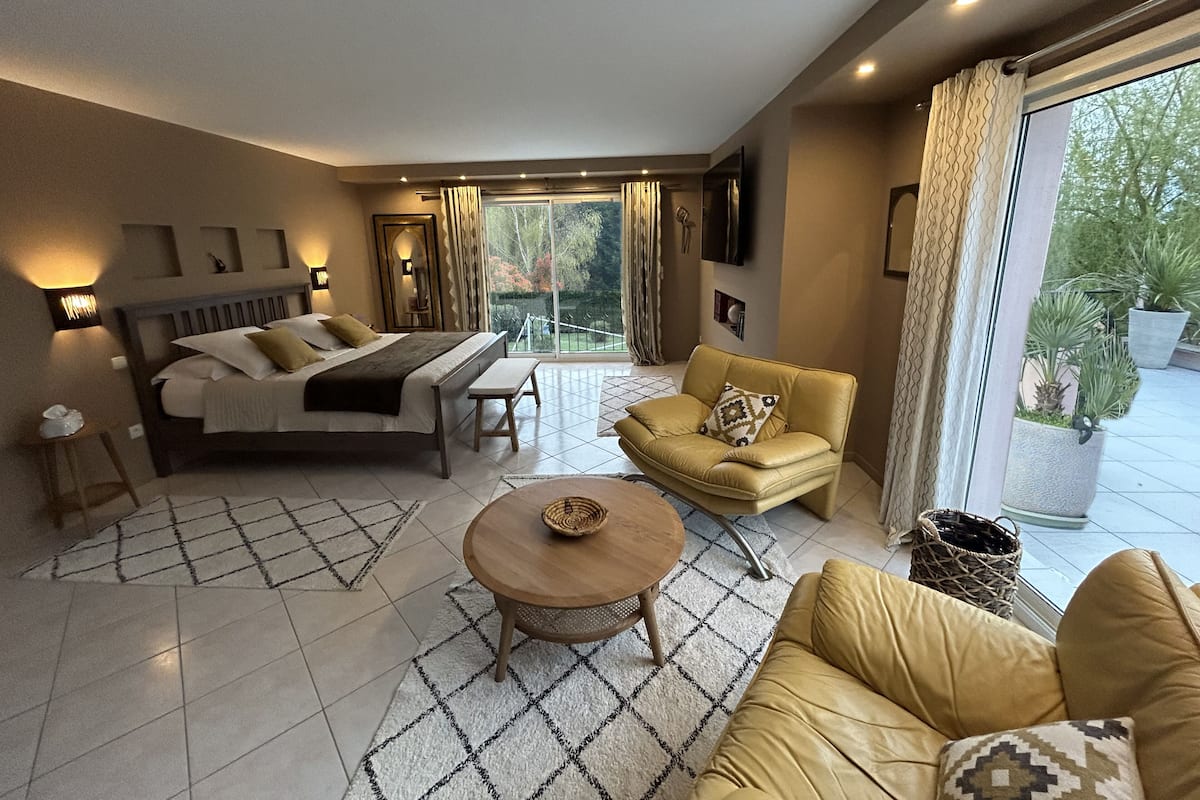 A modern bedroom with a bed, a sofa, a coffee table, and a TV.