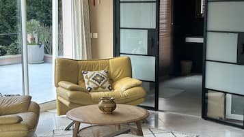 Un salon moderne avec un canapé jaune, une table basse ronde en bois et un coussin décoratif à motifs.
