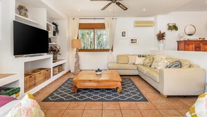 A living room with a TV, sofa, coffee table, and decorative items.