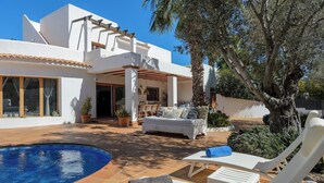 A modern villa with a swimming pool, outdoor seating, and a covered patio area.