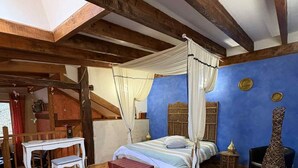 A room with a wooden ceiling, a bed with a canopy, a bench, a small table, and a suitcase. - La Charmante (Xertigny)