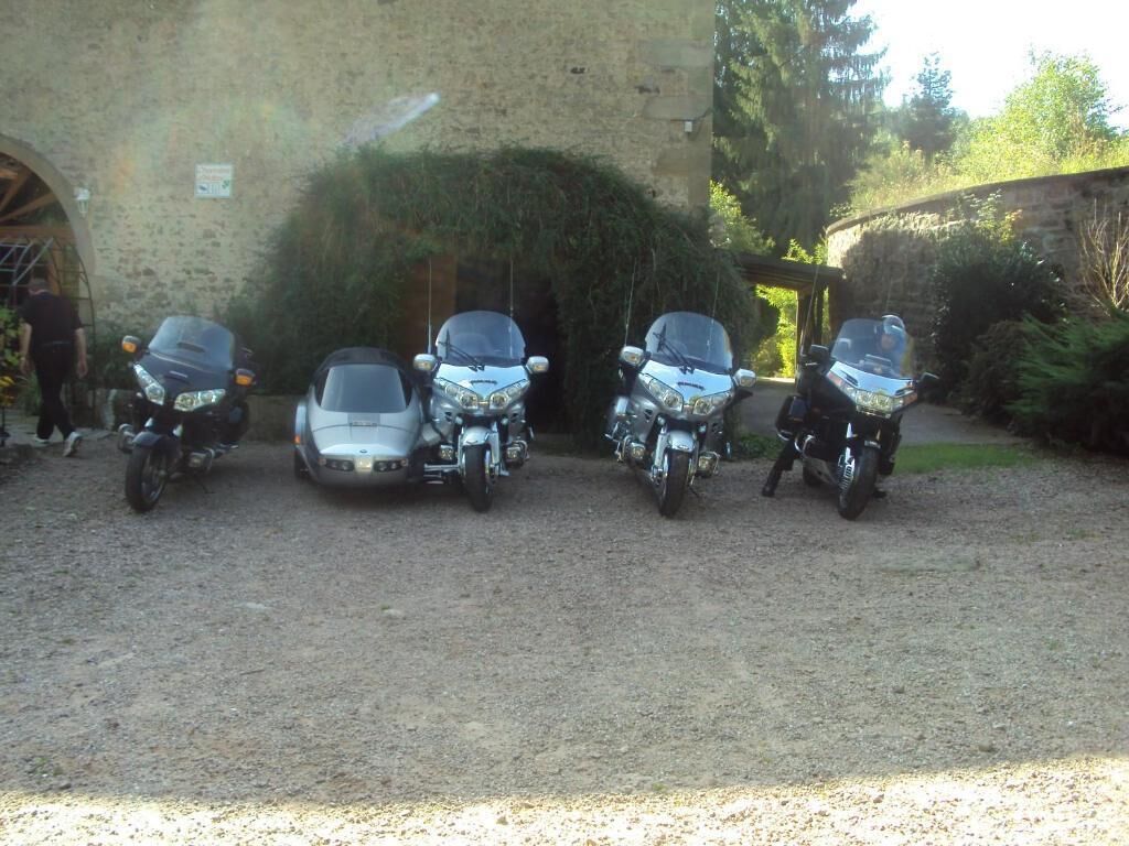 Une allée de gravier où sont garées quatre motos, côte à côte.