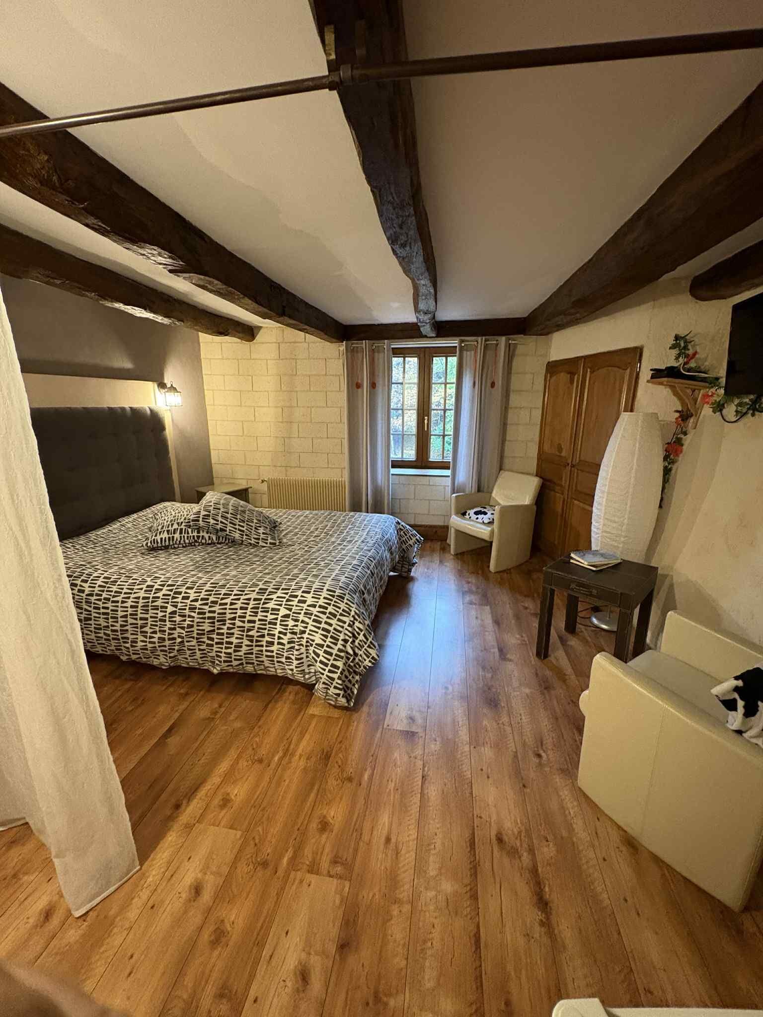 Ein gemütliches Schlafzimmer mit einem großen Bett, einer kleinen Couch und einem Fenster mit Vorhängen.