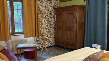 A cozy room with a bed, a red sofa, a wooden cabinet, and a window with curtains.