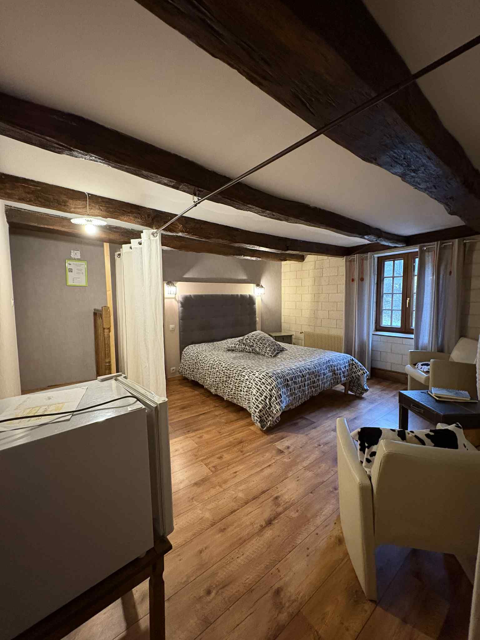 Ein Schlafzimmer mit einem Bett, einem Sessel, einem Schreibtisch und einem Fenster.