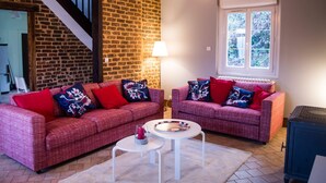 A living room with two red plaid sofas, a white coffee table, a lamp, and a large window with a view of greenery.