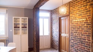A room with a brick wall, a wooden door, a white cabinet with glass doors, and a dining table with chairs.