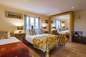 Een ruime slaapkamer met twee bedden, een grote spiegel en uitzicht op de stad.