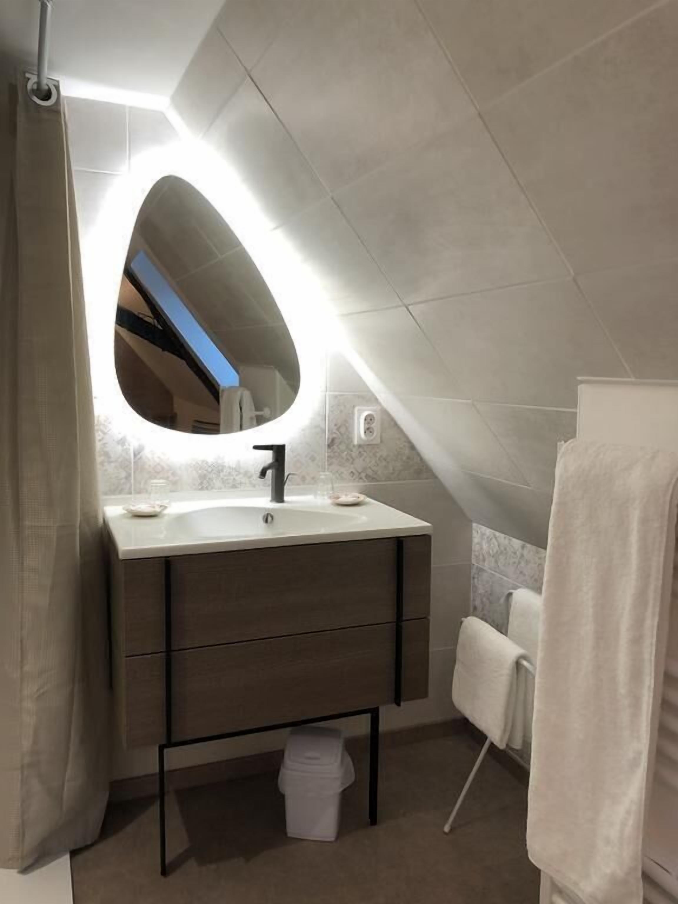 A modern bathroom with a vanity, mirror, and towel rack.