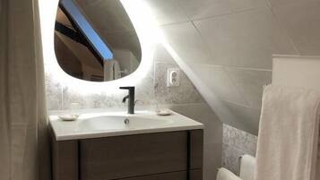 A modern bathroom with a vanity, mirror, and towel rack.