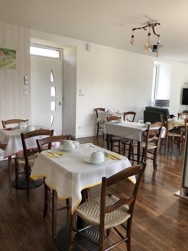Un comedor con varias mesas y sillas, un ventilador de techo y un televisor en la pared.