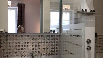 A modern bathroom with a glass shower enclosure, a white sink with a wooden countertop, and a tiled backsplash.