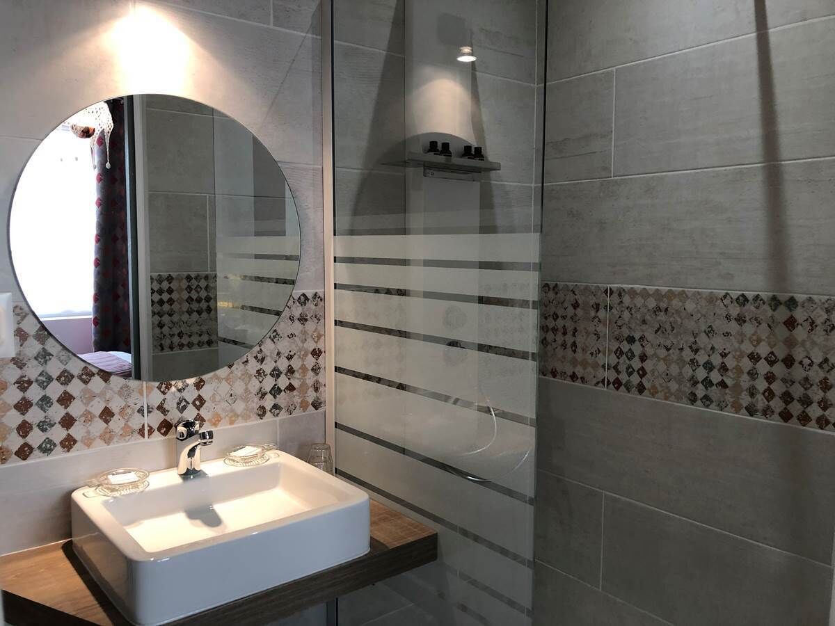 A bathroom with a white sink, a round mirror, and patterned tiles.