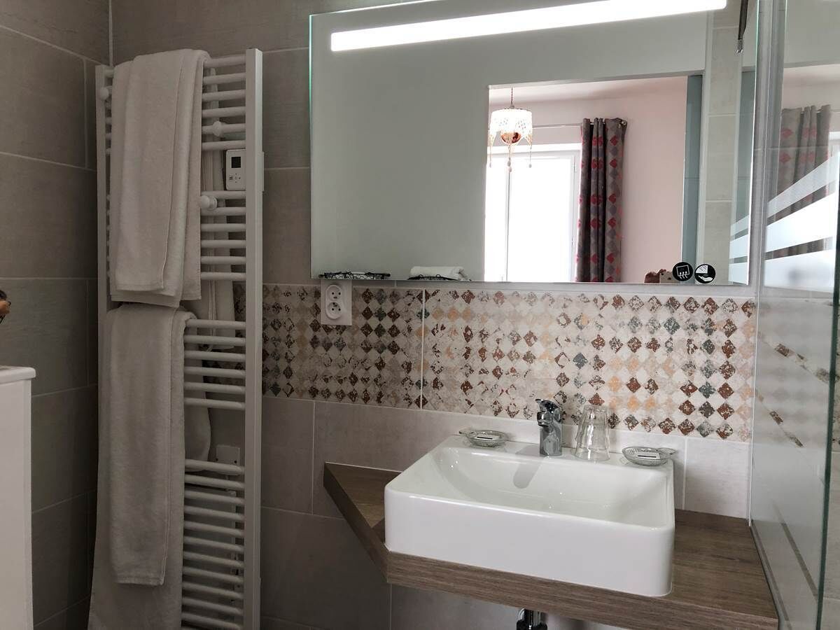 A bathroom with a white sink, a towel rack, and a mirror.