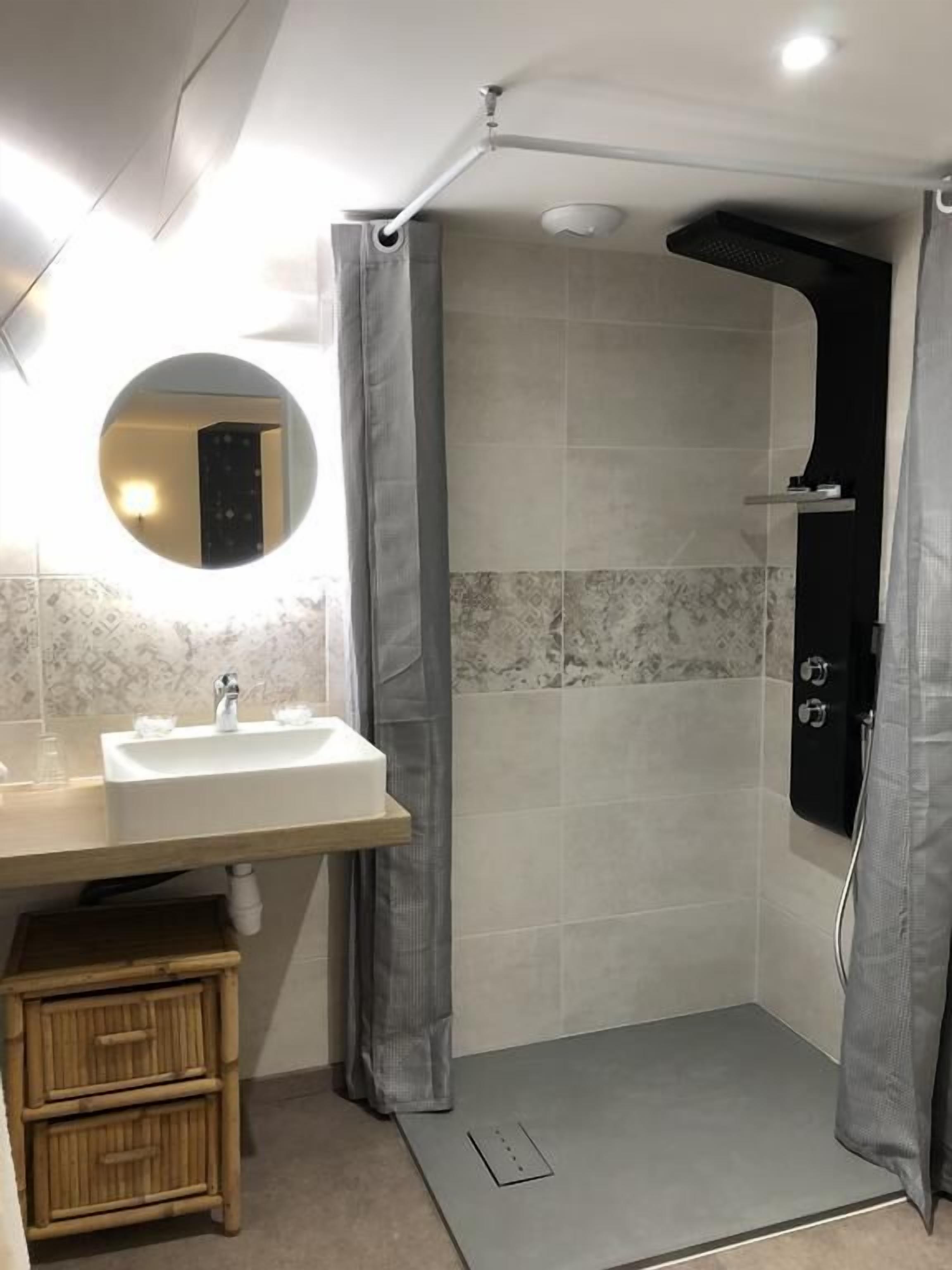 Een moderne badkamer met een douche, wastafel en spiegel.
