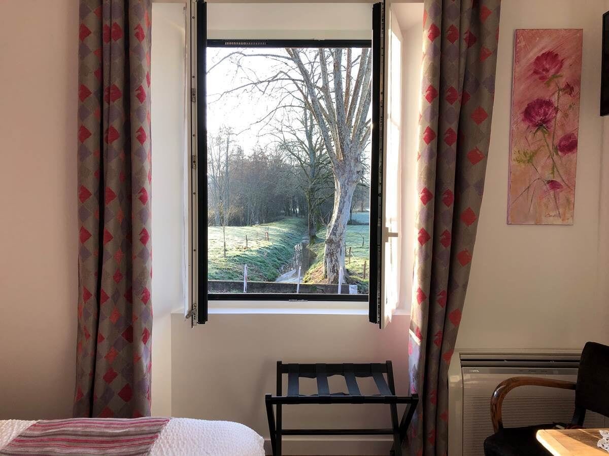 A bedroom with a window, a radiator, a bed, and a chair.