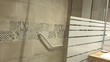A modern bathroom with a glass shower enclosure, a patterned tile backsplash, and a wooden vanity.