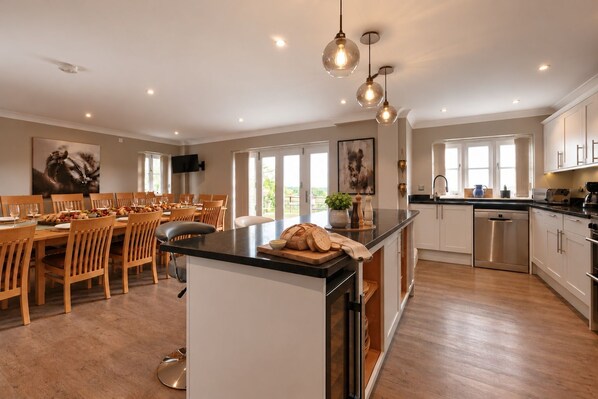 A modern kitchen with a central island, wooden dining table, and chairs.