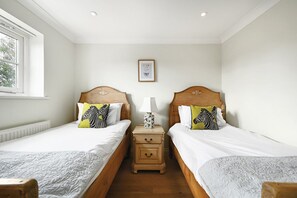 A hotel room with two single beds, a nightstand with a lamp, and a window with a view.