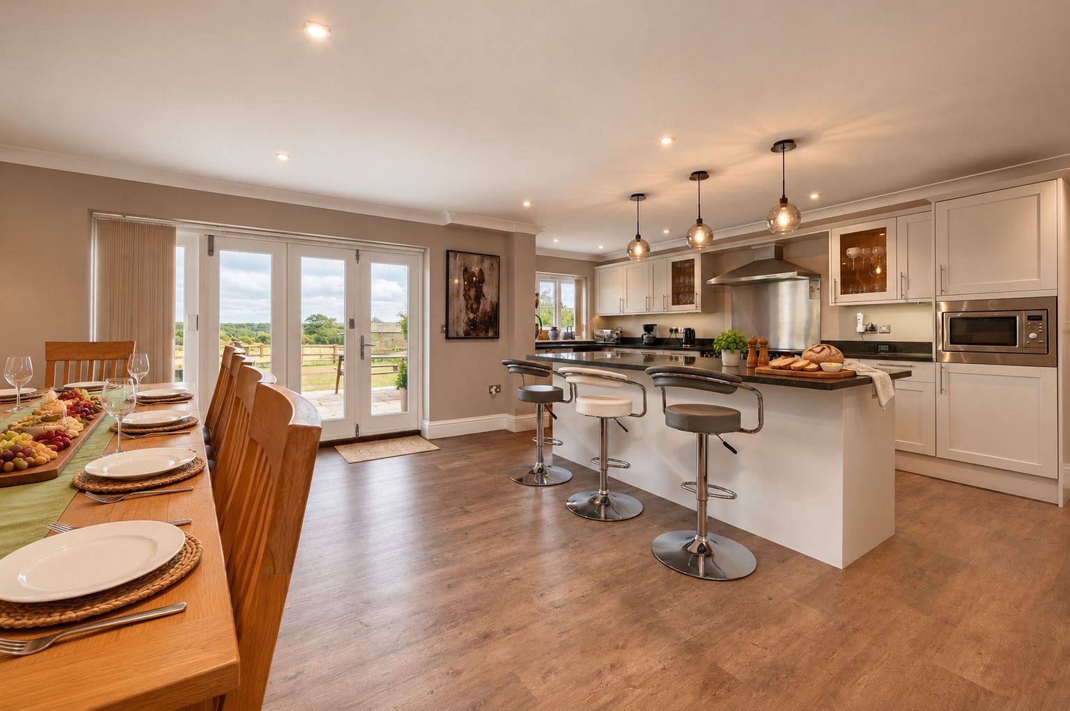 A spacious kitchen with a central island, bar stools, and a dining area with a view.