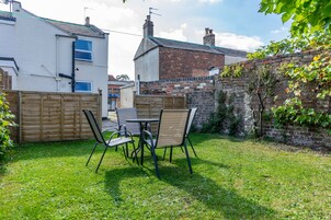 A backyard with a wooden fence, a brick wall, and a table with chairs.