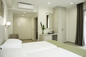 Quarto de hotel com cama, escrivaninha com espelho, guarda-roupa e ar condicionado.