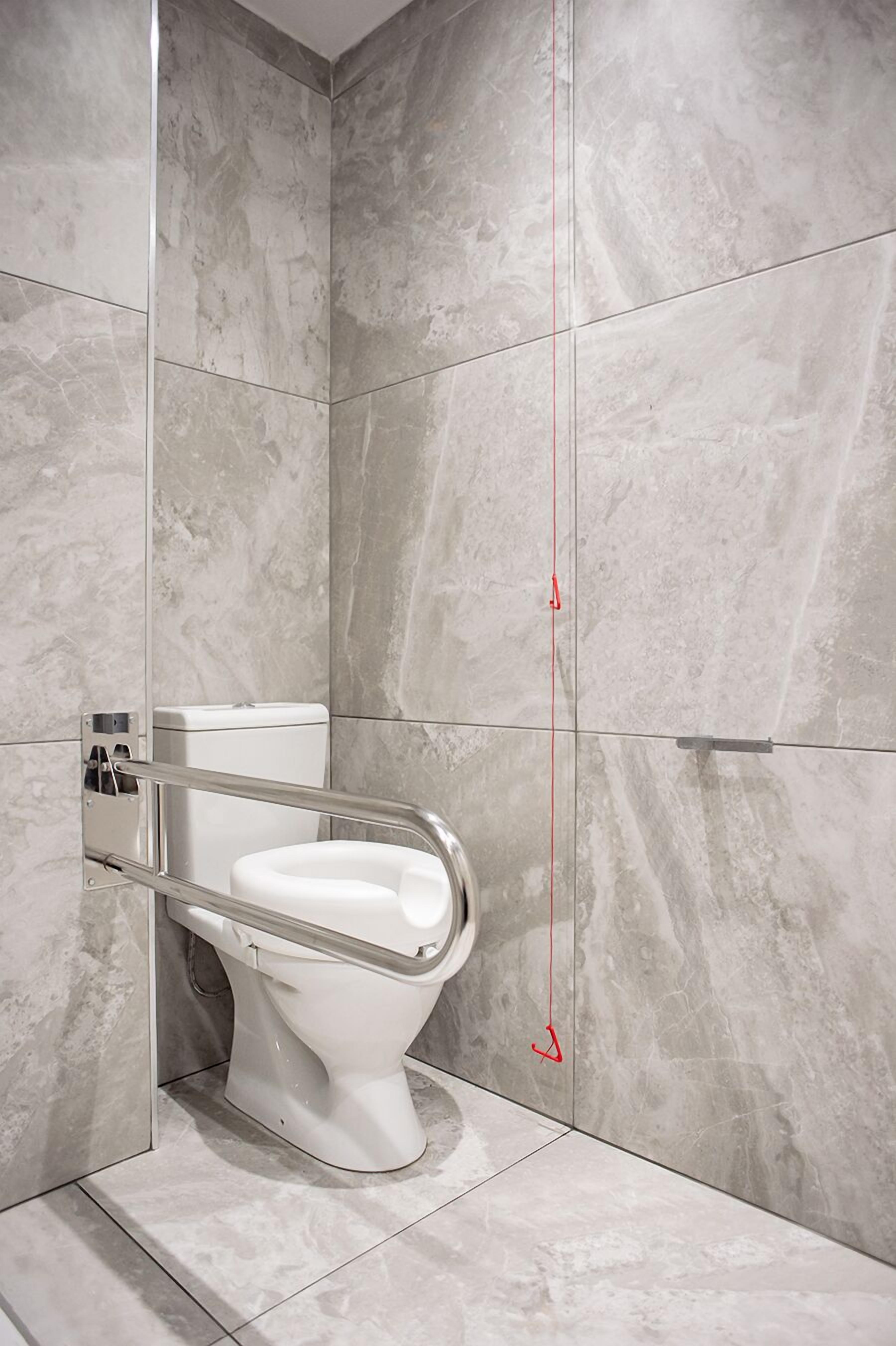 A modern bathroom with a white toilet, marble walls, and a red height marker.
