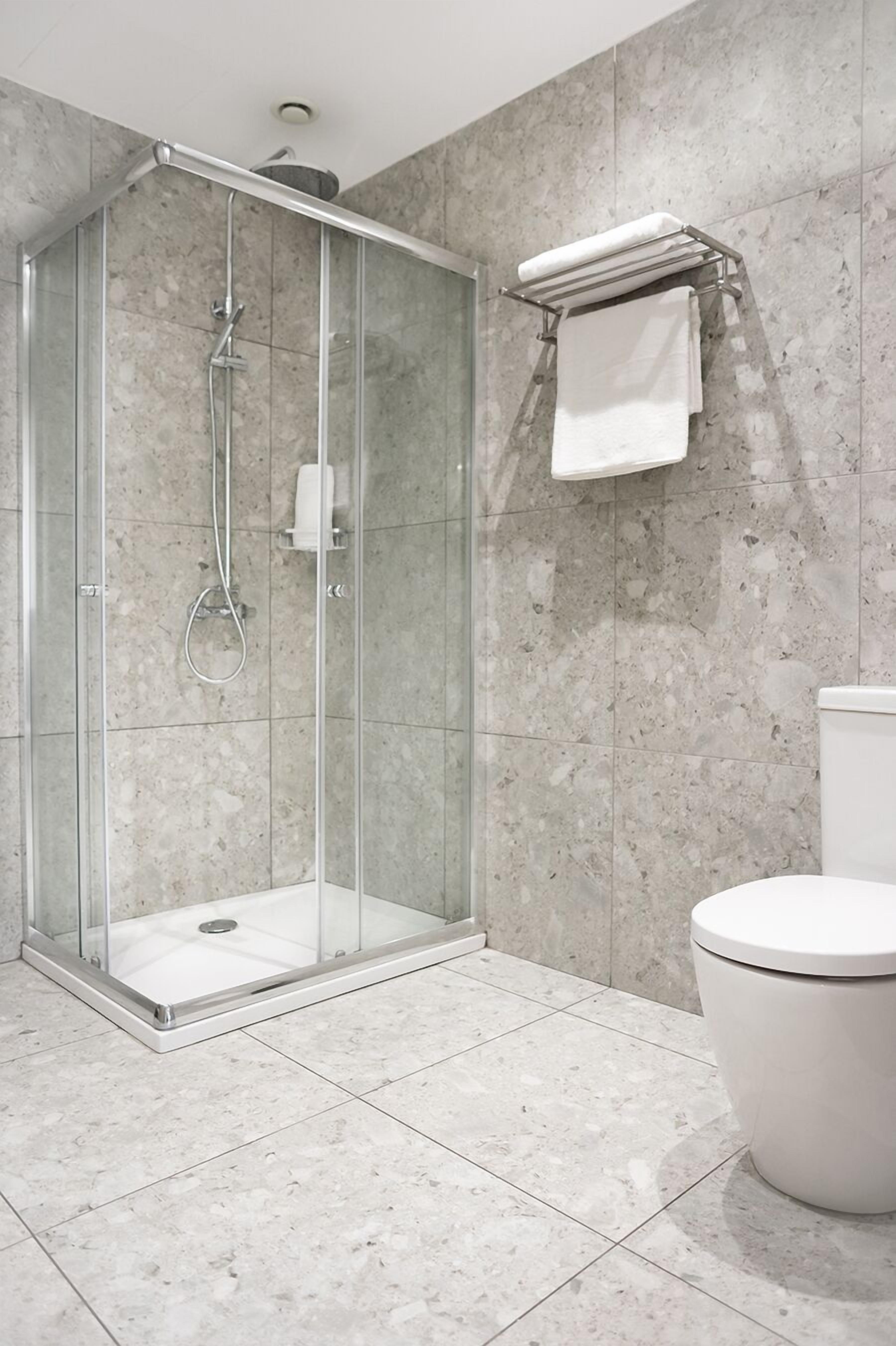 Ein modernes Badezimmer mit einer Duschkabine, einer Toilette und einem Handtuchhalter.