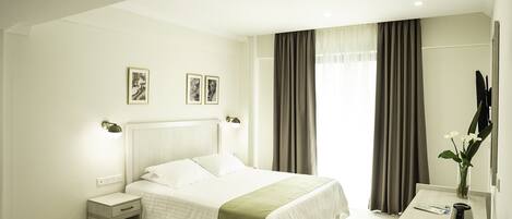 Une chambre d’hôtel moderne avec un grand lit, des tables de chevet, un bureau et un miroir.