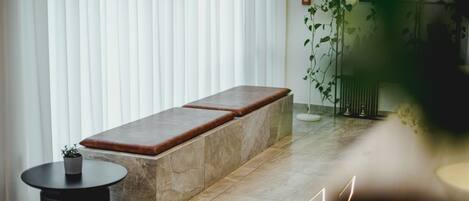 A modern room with a bench, a small round table, and a potted plant.