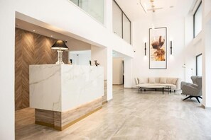 Um lobby moderno com um balcão de recepção de mármore, um sofá e uma cadeira.