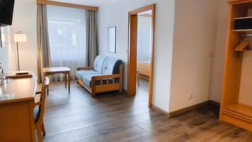 Een hotelkamer met een bed, bureau, stoel, klein tafeltje, kledingkast en televisie.