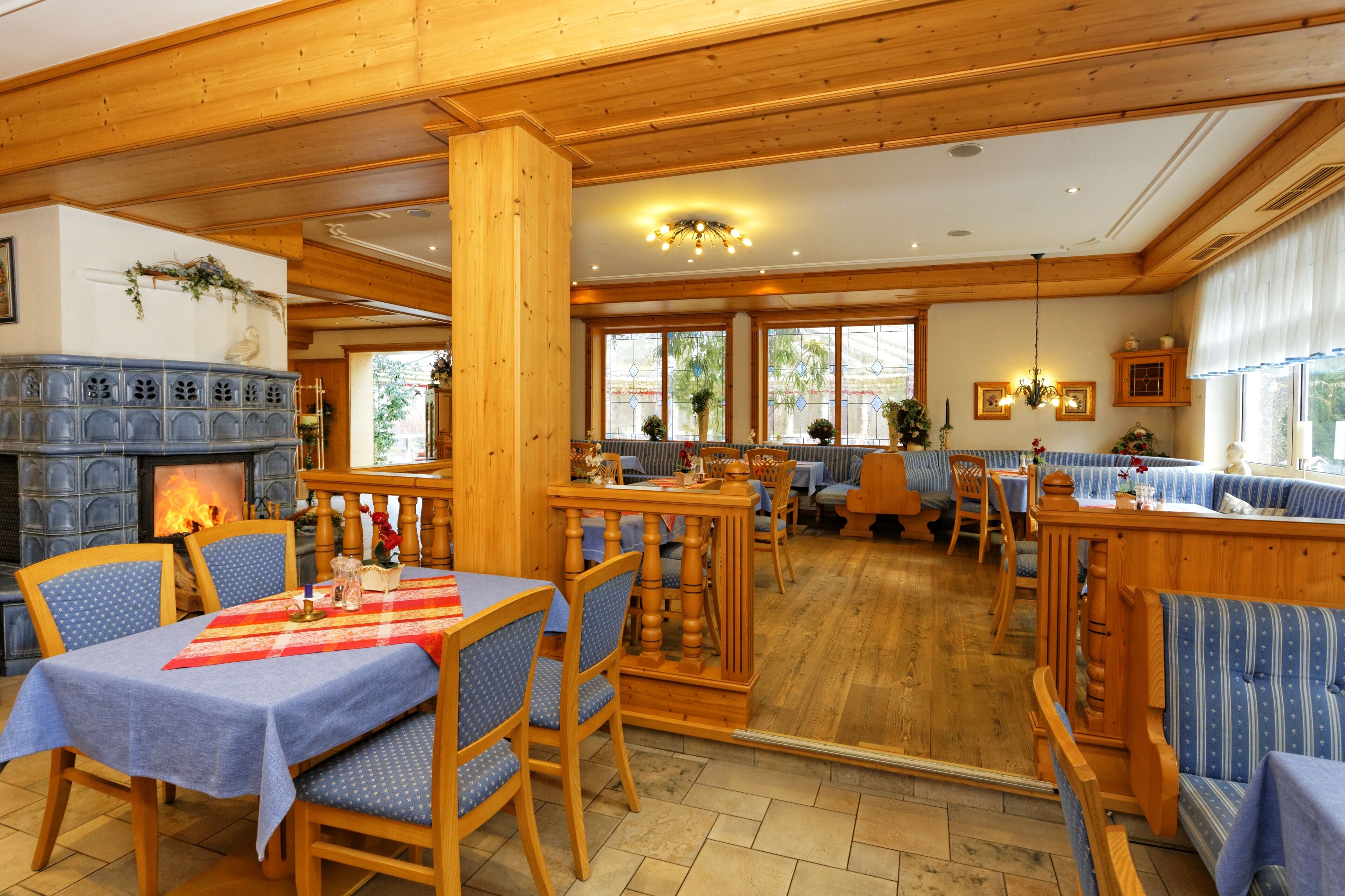 A cozy restaurant with wooden interiors, a fireplace, and blue upholstered seating.