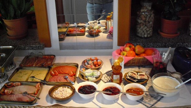 Een buffet met diverse gerechten, waaronder vleeswaren, kazen en sauzen.
