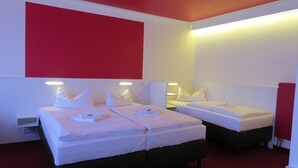 Een hotelkamer met twee bedden, witte beddengoed en rode accenten op de muren.