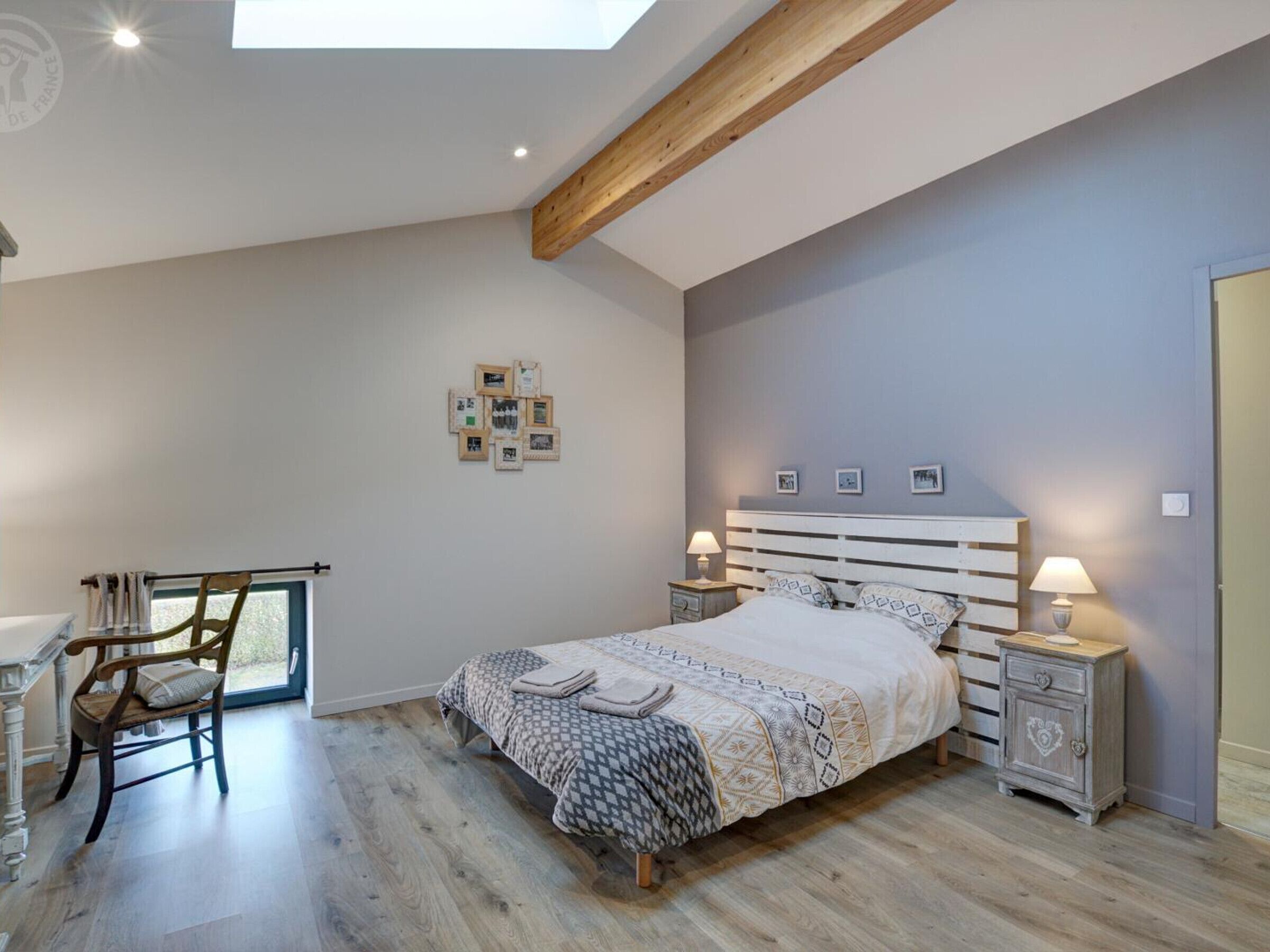 Een slaapkamer met een bed, nachtkastjes, een stoel en een bureau.