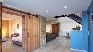 A spacious living area with a large sliding door, a stone wall, a sofa, and a kitchen area with a blue accent wall. - Spacious and bright family accommodation in Chazelles-sur-Lyon (Chazelles-sur-Lyon)