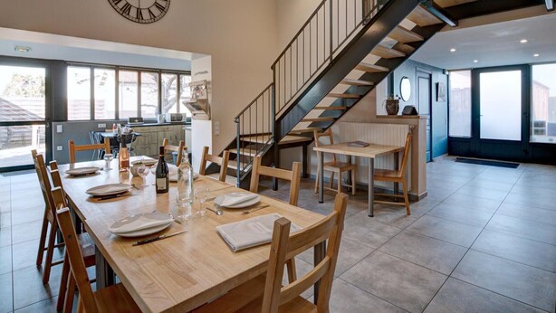 A spacious kitchen with a dining area, a large clock, and a staircase leading to an upper level. - Spacious and bright family accommodation in Chazelles-sur-Lyon (Chazelles-sur-Lyon)